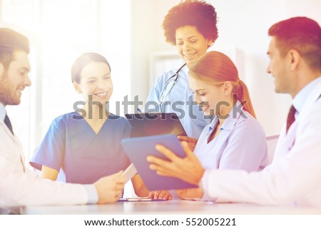 hospital, profession, people and medicine concept - group of happy doctors with tablet pc computers meeting at medical office Royalty-Free Stock Photo #552005221
