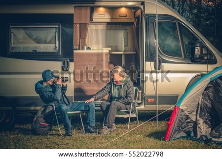Young Couples Having Fun on the Campsite. RV Motorhome Camping. Men Taking Picture of His Wife Using Digital Camera.