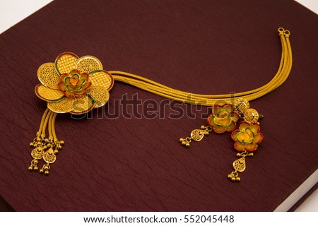 Necklace with floral design along with ear rings in brown texture. Royalty-Free Stock Photo #552045448