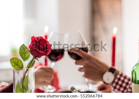 couple having a romantic dinner and toasting with cups of red wine. Royalty-Free Stock Photo #552066784