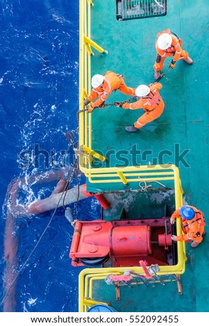 Offshore workers consist of riggers performing anchor handling activities on construction barge at oil field