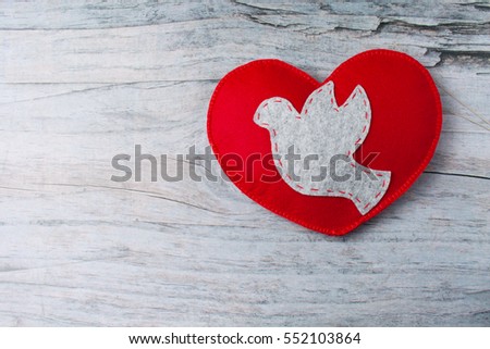 Hand made felt colorful heart with dove on wooden background with copy space. Craft element for Valentine's Day romantic greeting card.