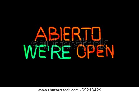 Close up view of an English-Spanish  neon sign with the words open and Abierto
