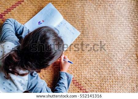 thai mixed race young little kid girl training writing on paper with pen on mat for hobby, countryside lifestyle