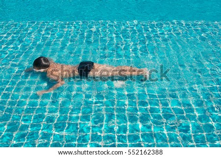 Young boy floating in swimming pool