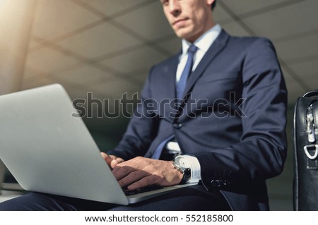 Serious man working on a laptop. Horizontal outdoors shot. Royalty-Free Stock Photo #552185800