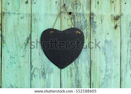 Blank black slate heart sign hanging from rope on rustic antique mint green wooden background; Valentines Day, Mothers Day and love concept with painted and chalkboard copy space