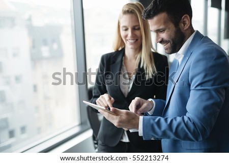Happy business colleagues in modern office using tablet Royalty-Free Stock Photo #552213274