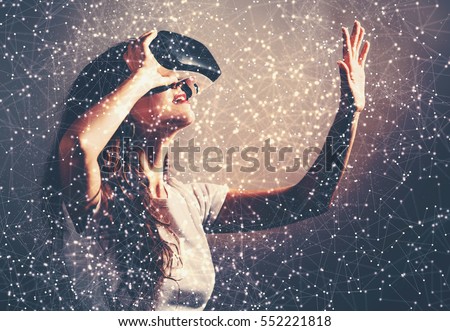 Young woman using a virtual reality headset with conceptual network lines Royalty-Free Stock Photo #552221818
