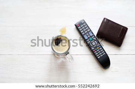 Beer glass, panel for the TV and a wallet on a white wooden surface