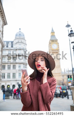 Beautiful girl taking selfie on phone on street of London

