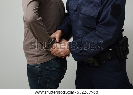 Closeup of a policeman handcuffing an illegal man.