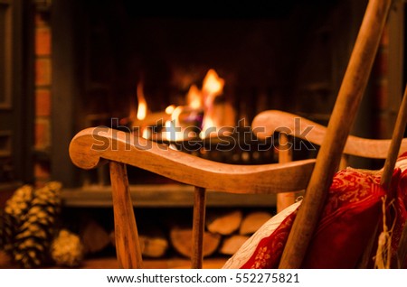 Vintage Wood Rocking chair and fireplace with burning fire. Cozy winter background Royalty-Free Stock Photo #552275821