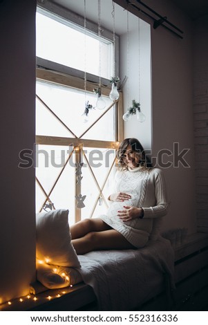  A pregnant woman. New year. Sitting on the window.