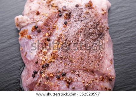 raw meat of pork for roasting or barbecue with spices, on a black background, with space for text