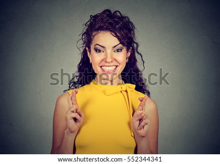 Closeup portrait woman crossing her fingers, hoping, making a wish isolated on gray wall background. Human face expression, emotions, feeling