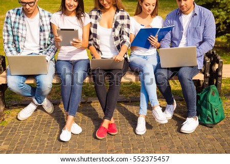 Close up photo of happy diverse classmates sitting on bench and studying
