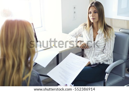 Young female international student having consultation with business coach before upcoming examination testing during individual meeting in university library using laptop computer and 5G wireless
