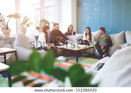 Crew of talented bloggers enjoying work break in friendly atmosphere during creating advertising company for new model drone using laptop computer,wireless connection to internet in coworking place Royalty-Free Stock Photo #552386920