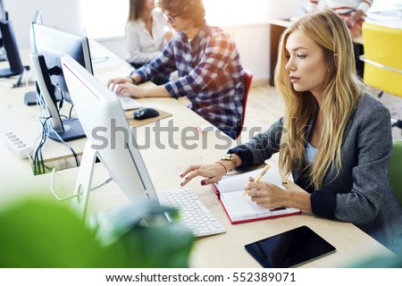 Attractive female international student making individual online testing and writing composition for annual exams preparation using computer,wireless connection to internet during lesson in library Royalty-Free Stock Photo #552389071