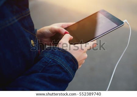 Cropped image of female hands holding modern touchpad with mock up screen while texting messages in online chat using wireless connection to network standing on copy space area for your advertising