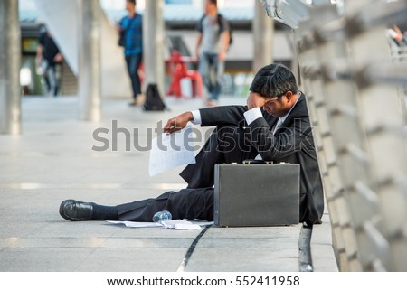 business man frustrated he sad for lost work sit on street upset fail unhappy after Fired from job from covid19 in black suit. Many employee are unemployed to reduce expenses salary income.dismissal  Royalty-Free Stock Photo #552411958