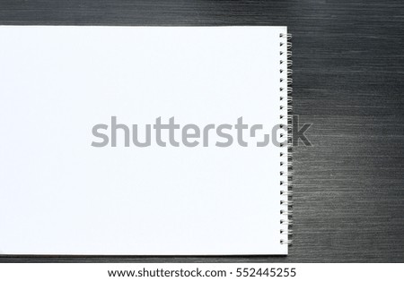 Blank notepad for sketching with white pages on black wooden table..