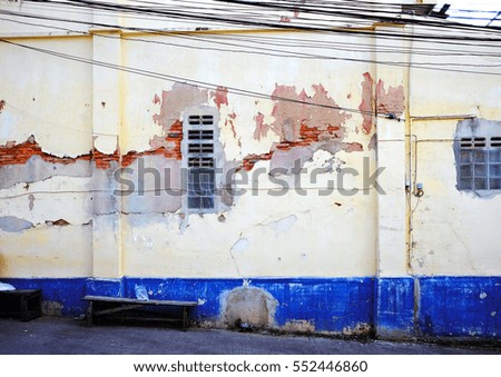 Old building wall with cracked paint and concrete surface.