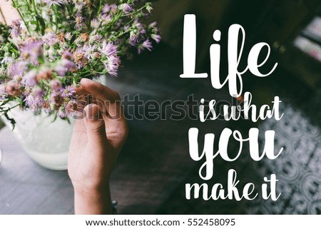 Life quote. Motivation quote on soft background. The hand touching purple flowers. Life is what you make it.