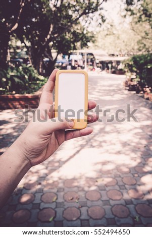 Vintage tone of Cropped shot view of hands holding smart phone with blank copy space screen for your text message or information content, female reading text message on phone during in urban setting.