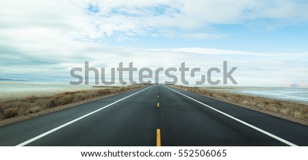The black road heading straight ahead. Flanked by the sea Royalty-Free Stock Photo #552506065