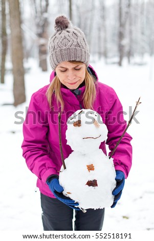 Picture of a beautiful young woman holding a little snowman in her hands