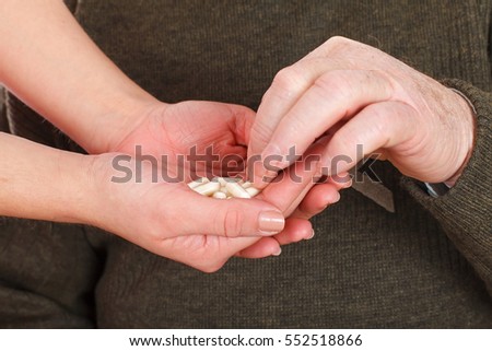 Close up picture of a senior man receiving his pills from his caregiver