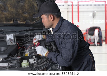 Professional Auto mechanic uses a voltmeter to check the voltage level of a Car Fuse box, Control engine lighting. Car electrical at repair shop