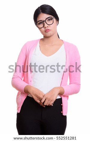 Studio shot of young Asian nerd woman looking sad isolated against white background