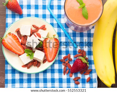 Ingredients for smoothie with tofu cheese, strawberries, bananas and goji berries on checkered napkin