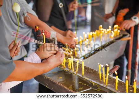 people hand lighting candles in a church