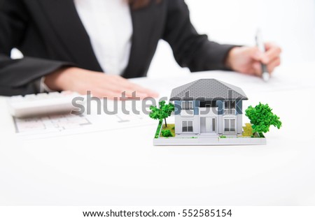 Real estate agent signs contract behind home architectural model