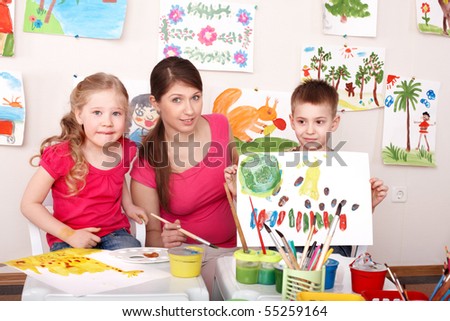 Children painting with teacher in art class. Child care.