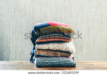 Many color cozy knitted sweater on a wooden table. Winter style. Royalty-Free Stock Photo #552605599