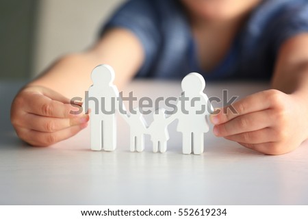 Child holding figure in shape of happy family, closeup. Adoption concept Royalty-Free Stock Photo #552619234