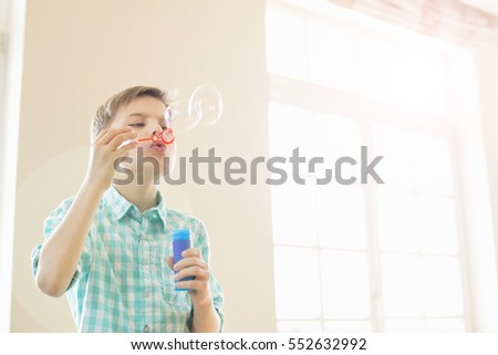 Boy blowing bubbles at home