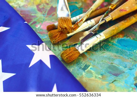 artist's palette with paints and a brush for drawing on a background of the American flag of the USA