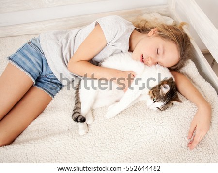 Child sleeping with cat. Girl with pet at home