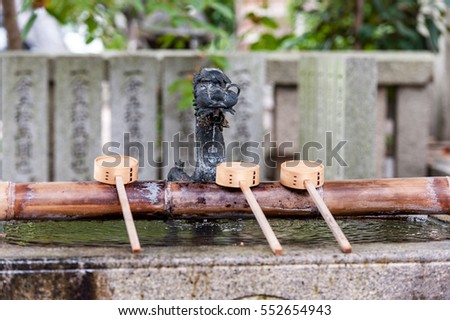 Wooden Water Spoon and Pouring Water in Kyoto Shrine Backyard.