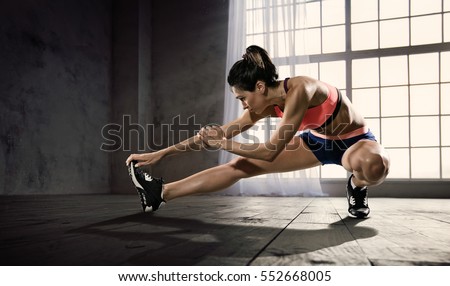 Sports. Woman at the gym doing stretching exercises and smiling on the floor Royalty-Free Stock Photo #552668005