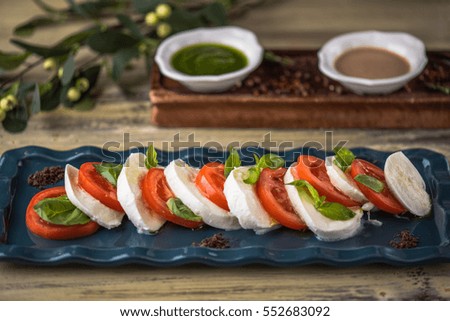 Appetizer salad of tomatoes and cheese close-up on a wooden table.