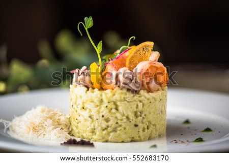 Risotto with seafood. Rice in white plate close-up on a black background. Royalty-Free Stock Photo #552683170