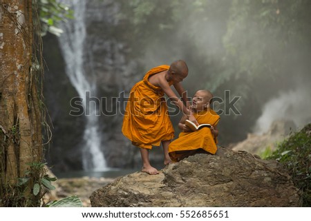 Novice Monk  thailand playing in the nature around of them stay outdoors Waterfall background, in Thailand 