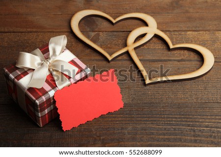 Gift box with decorative hearts on a wooden background.